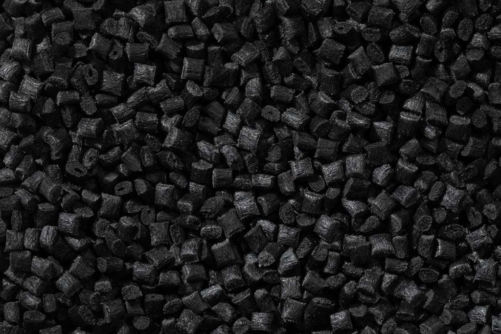 Fine black powder is staged in a processing or lab setting. Biochar can be refined into carbon fillers for engineered material formulations.